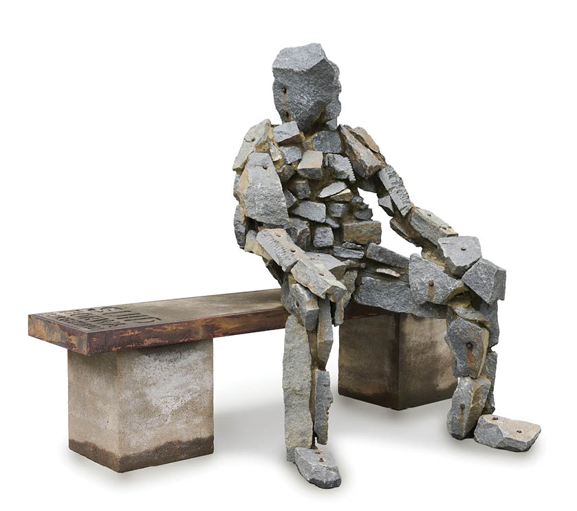 A statue of a man sitting on a bench. Description generated by AI