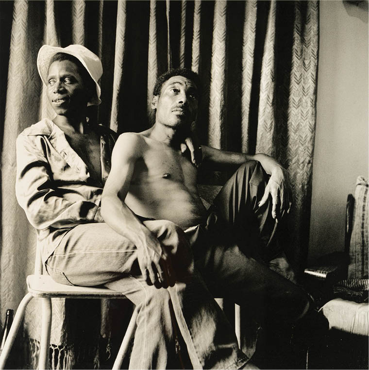 Two men sitting on a chair. Description generated by AI
