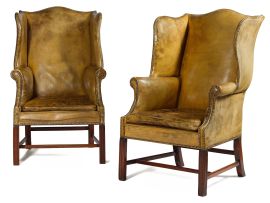 A pair of George III style mahogany and close-nailed leather-upholstered wingback armchairs