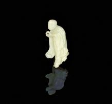 A Chinese carved pale celadon jade figure of a Lohan, late 19th/early 20th century