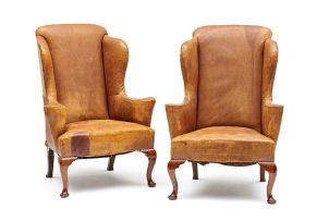 A pair of George II style brown leather and mahogany wing-back armchairs