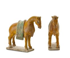 A pair of Chinese mustard- and green-glazed pottery horses, Tang Dynasty