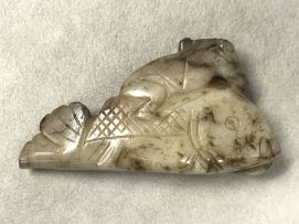 A Chinese mottled grey and white jade carving of a small boy astride a fish, Qing Dynasty, 19th/20th century