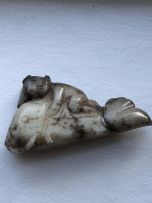 A Chinese mottled grey and white jade carving of a small boy astride a fish, Qing Dynasty, 19th/20th century